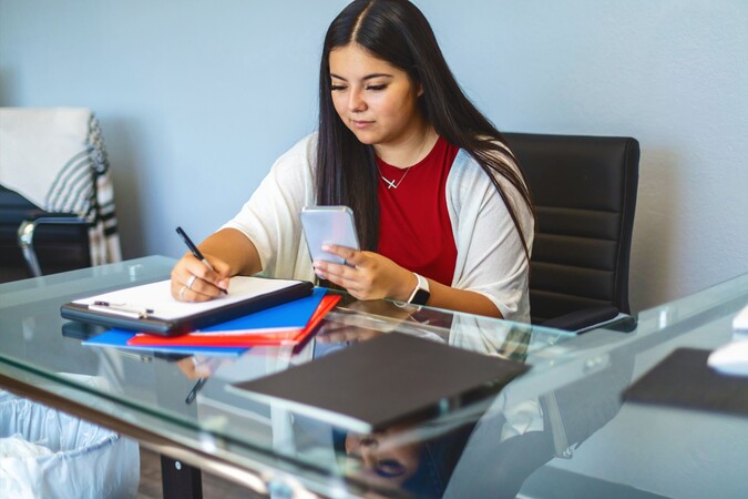Woman at desk using cell phone